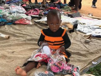 Little_girl_amusing_herself_while_her_mum_works_at_Nyaishozi_market